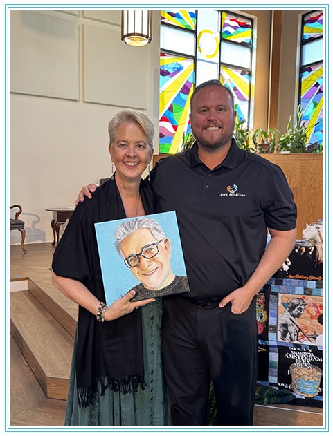Tracy and Brent holding the painted portrait of Tom at his celebration of life