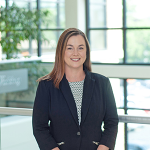 Professional woman in business attire smiling indoors.