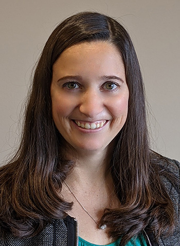 Smiling woman with long brown hair in a casual setting.