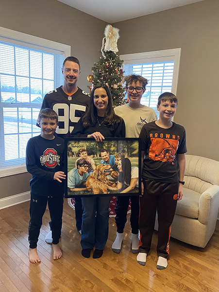 A family holding a colorful artwork in a cozy living room.